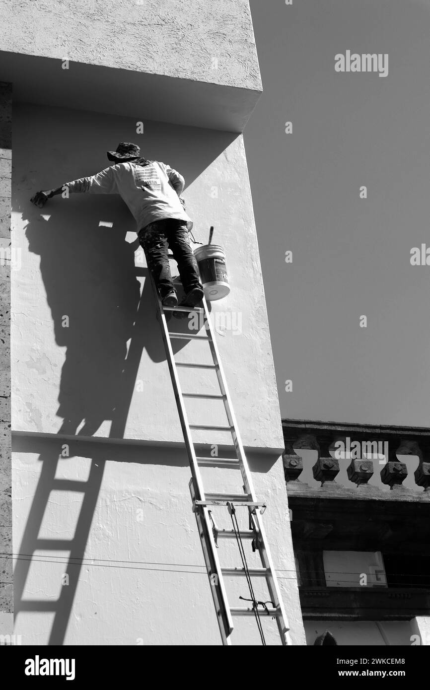 Ein Mann, der an einer Wand eines Gebäudes arbeitet. Stockfoto