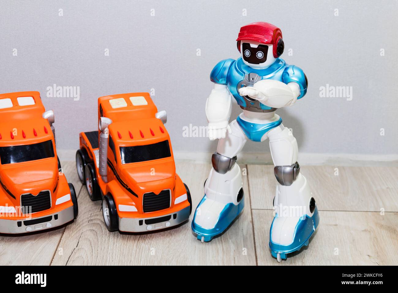 Auf dem Boden befinden sich Kinderspielzeugautos aus Kunststoff und ein Roboter. Stockfoto
