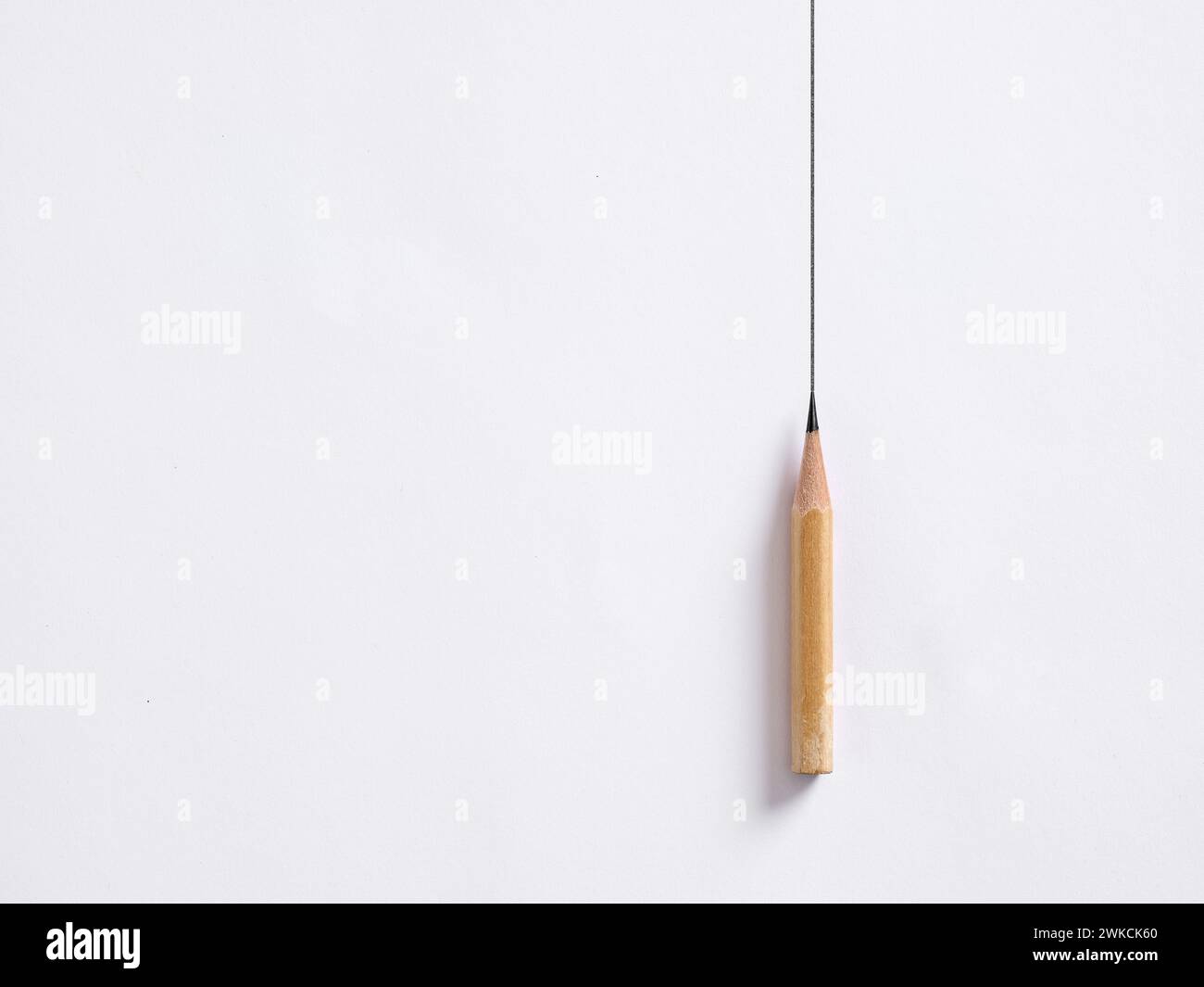 Der Bleistift zeichnet eine vertikale Linie auf weißem Hintergrund. Zeichnungsrahmen. Stabilität oder Stagnanz im Geschäft. Stockfoto