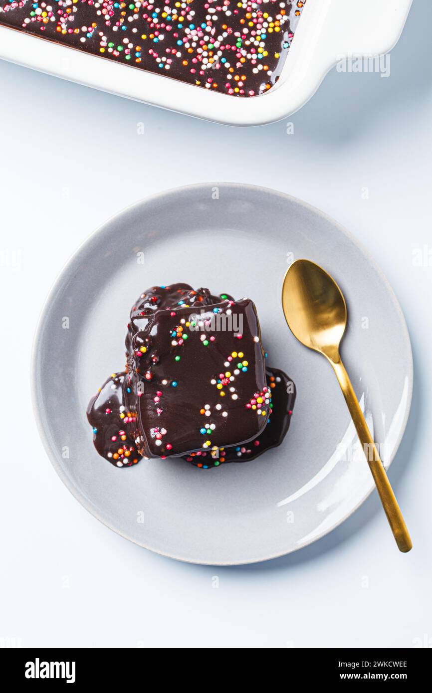 Ein Stück klassischer Schokoladen-Brownie-Kuchen mit farbigen Streuseln. Stockfoto