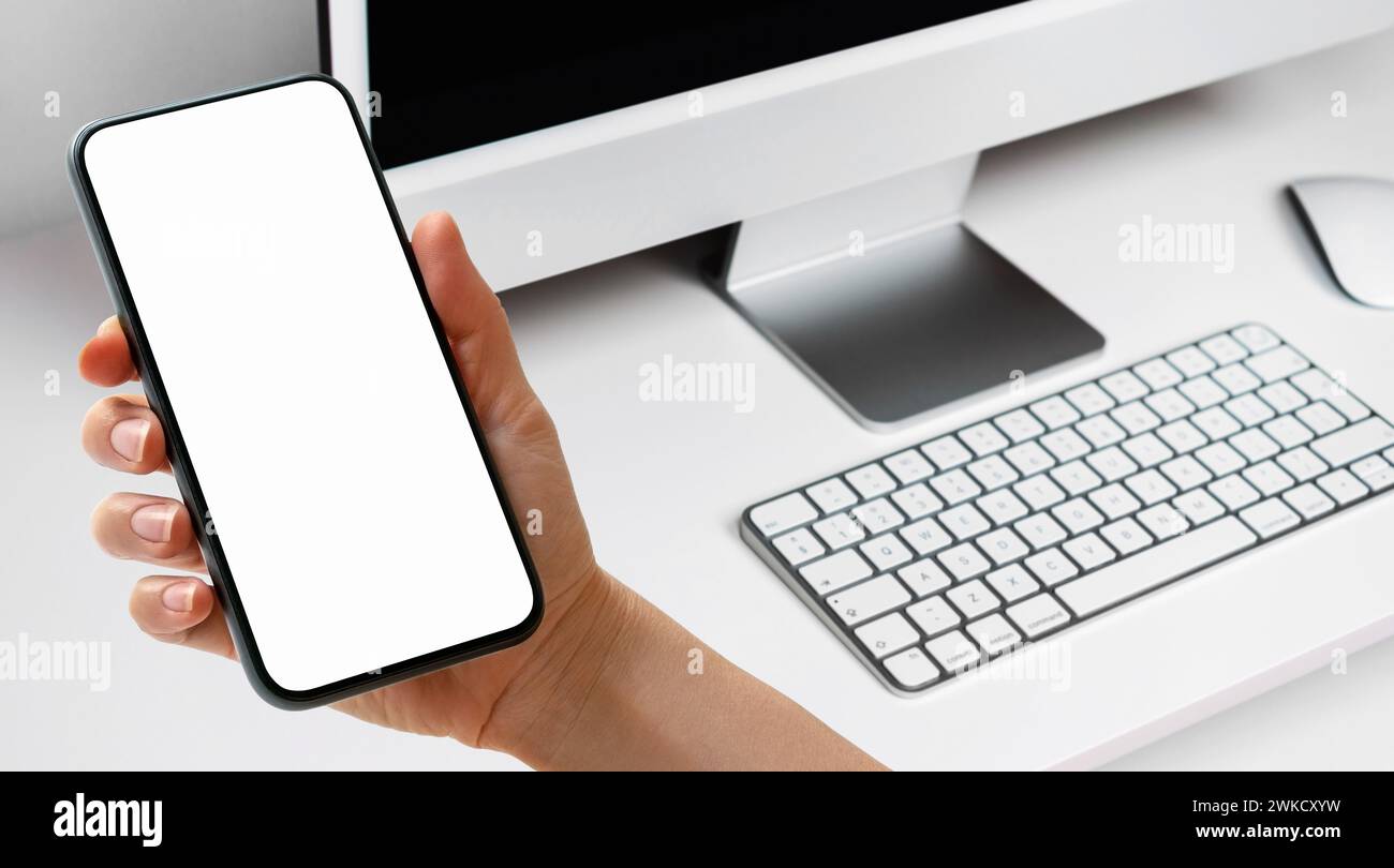 Smartphone mit Touchscreen in weiblicher Hand über Computertastaturen. Mockup für E-Commerce und elektronisches Banking für mobile Apps. Stockfoto