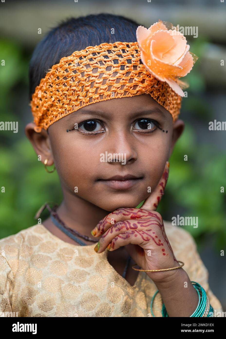 Außenporträt eines Mädchens auf der hinduistischen Hochzeit mit orangefarbenem Stirnband mit Blumen- und Henna-Dekoration auf der Hand Stockfoto