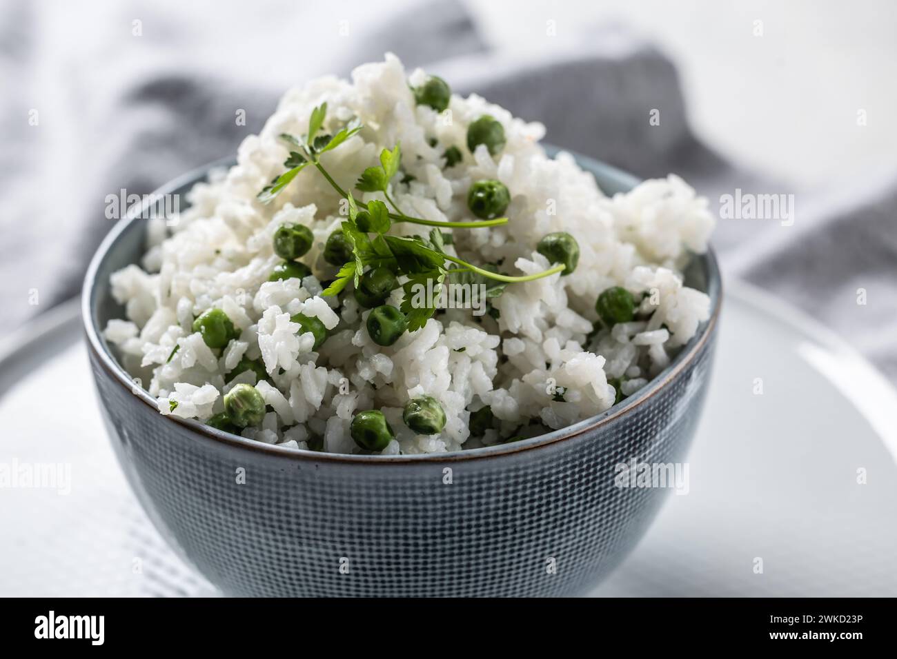 Jasminreis mit Erbsen und Petersilie in einer Schüssel auf dem Tisch. Stockfoto