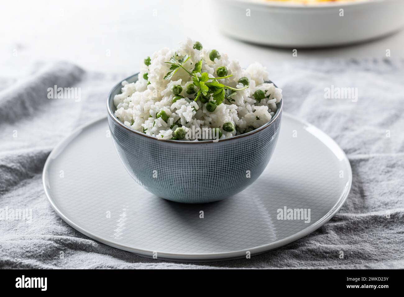 Jasminreis mit Erbsen und Petersilie in einer Schüssel auf dem Tisch. Stockfoto