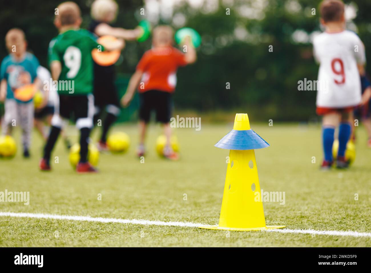 Anonyme Kinder spielen an einem sonnigen Sommertag Sport mit einem Trainer. Kinderfußball-Trainingsszene. Fußballtraining für Kinder. Kinder glücklich Stockfoto