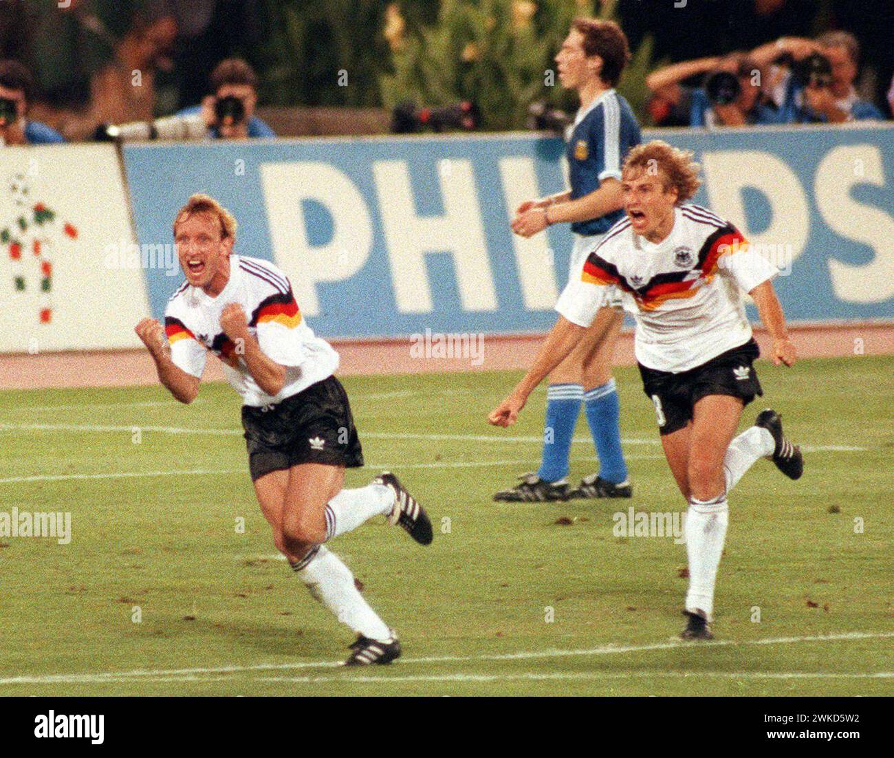 FILED - 08 Juli 1990, Italien, Rom: Der ehemalige deutsche Nationalspieler Andreas Brehme (l) und Jürgen Klinsmann laufen über das Spielfeld des Olympiastadions in Rom, um zu feiern, nachdem Brehme einen Elfmeter für Deutschland erzielte 1-0 Vorsprung. Die deutsche Mannschaft besiegte Argentinien im Finale der Weltmeisterschaft mit 1:0. Fußball-Weltmeister Andreas Brehme starb im Alter von 63 Jahren, wie seine Familie am Dienstag vor der Deutschen Presseagentur bestätigte. (Zu dpa: 'Fußball-Weltmeister Andreas Brehme starb') Foto: Frank Kleefeldt/dpa Stockfoto