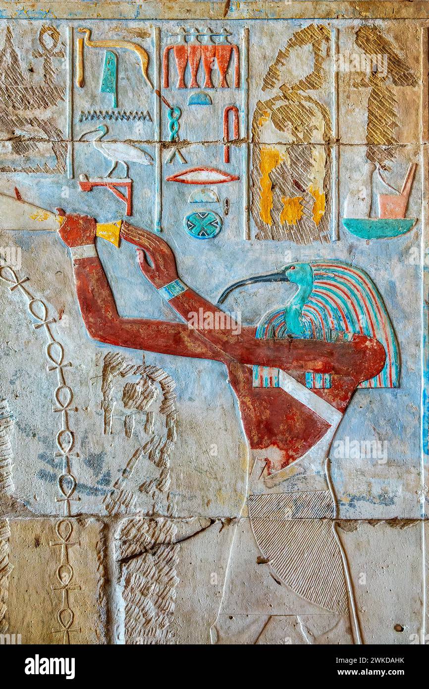 Schnitzerei mit bunten Hieroglyphen und Thoth mit einem Ibis Kopf, Inneres des Karnak Tempels in Luxor, Ägypten. Thoth ist der ägyptische Gott des Schreibens, der Magie, Stockfoto
