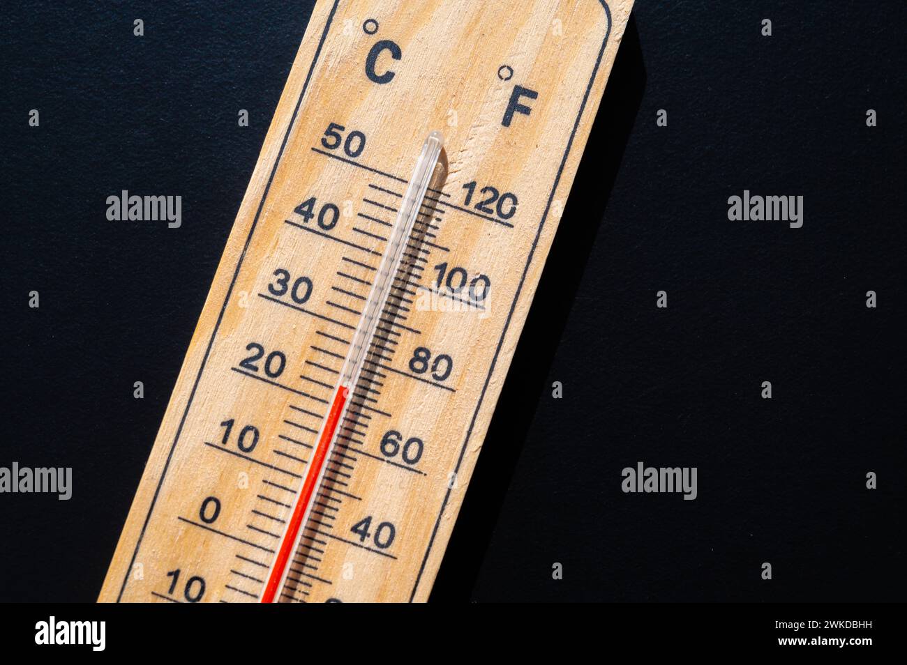Thermometer auf dunkler Oberfläche. Steigende Temperaturen und globale Erwärmung. Stockfoto