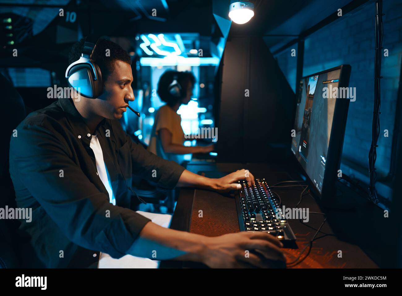 Ein Spieler verwendet einen Computer, um Videospiele mit Kopfhörern zu spielen Stockfoto