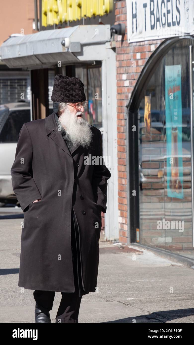 Ein älterer orthodoxer jüdischer Mann läuft auf der Lee Avenue mit einem russischen Karakul-Pelzhut. In Williamsburg, Brooklyn, New York City. Stockfoto