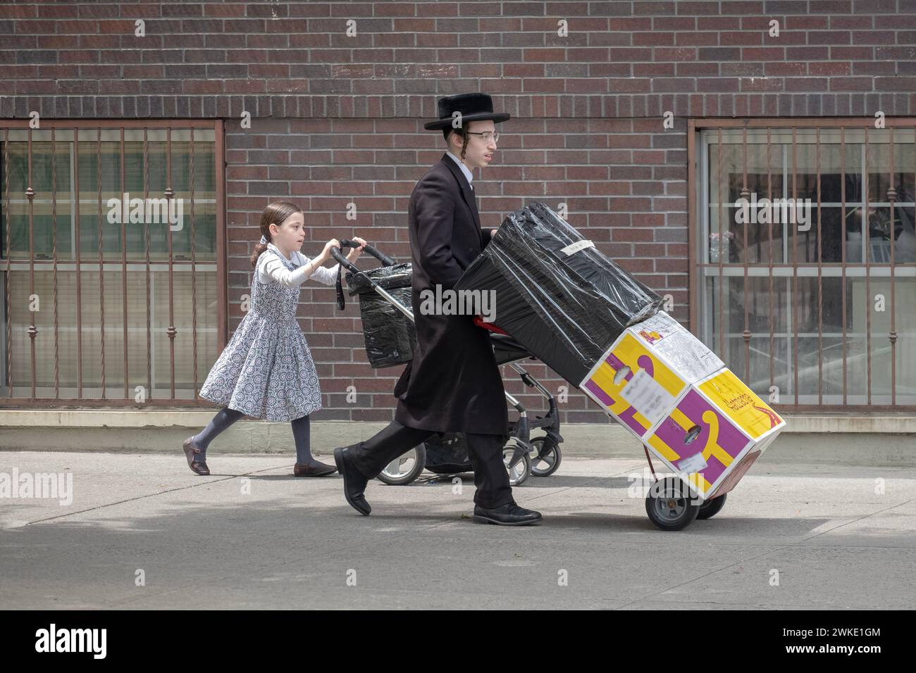 Ein chassidischer Bruder und ein Schwesterrad, das zu einem Bus zum Sommerlager fuhr. In Brooklyn, New York. Stockfoto