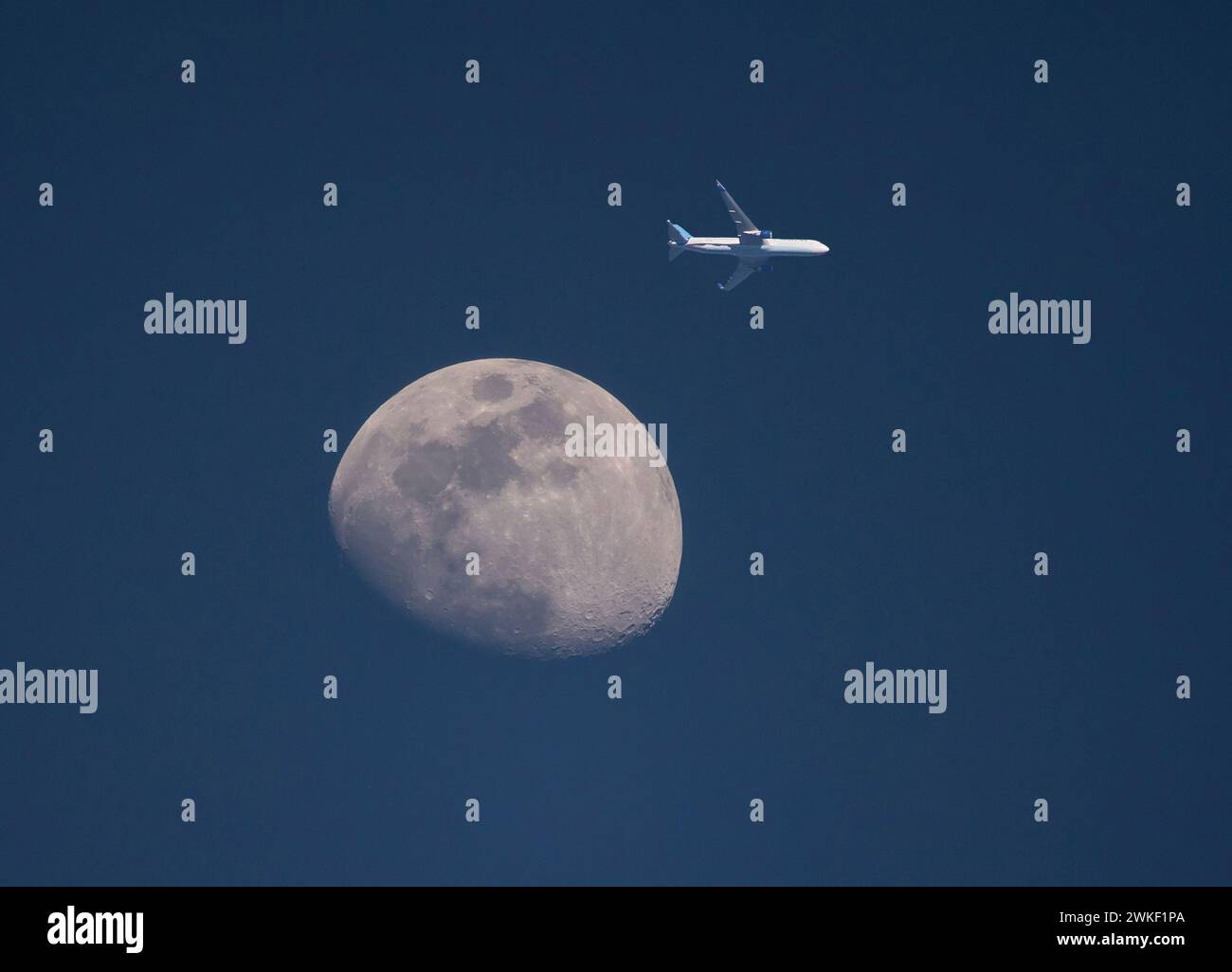 Ein kommerzielles Flugzeug kommt bei Sonnenuntergang in geringer Höhe am Mond vorbei. Stockfoto