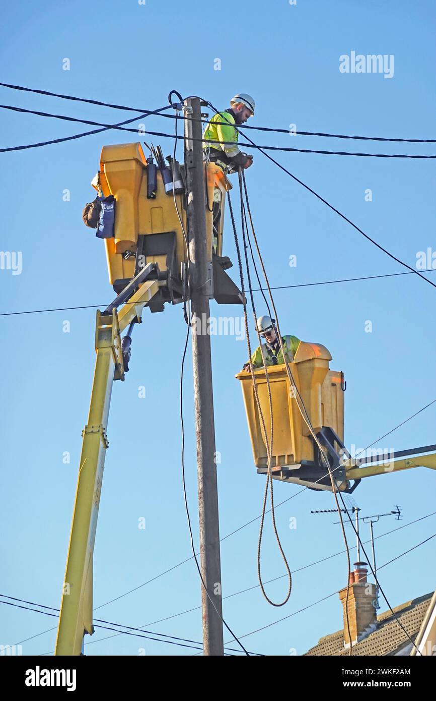 Elektroingenieure, die in Wohngebäuden arbeiten, die am Wintertag des blauen Himmels in England Großbritannien die Oberleitungen ersetzen Stockfoto