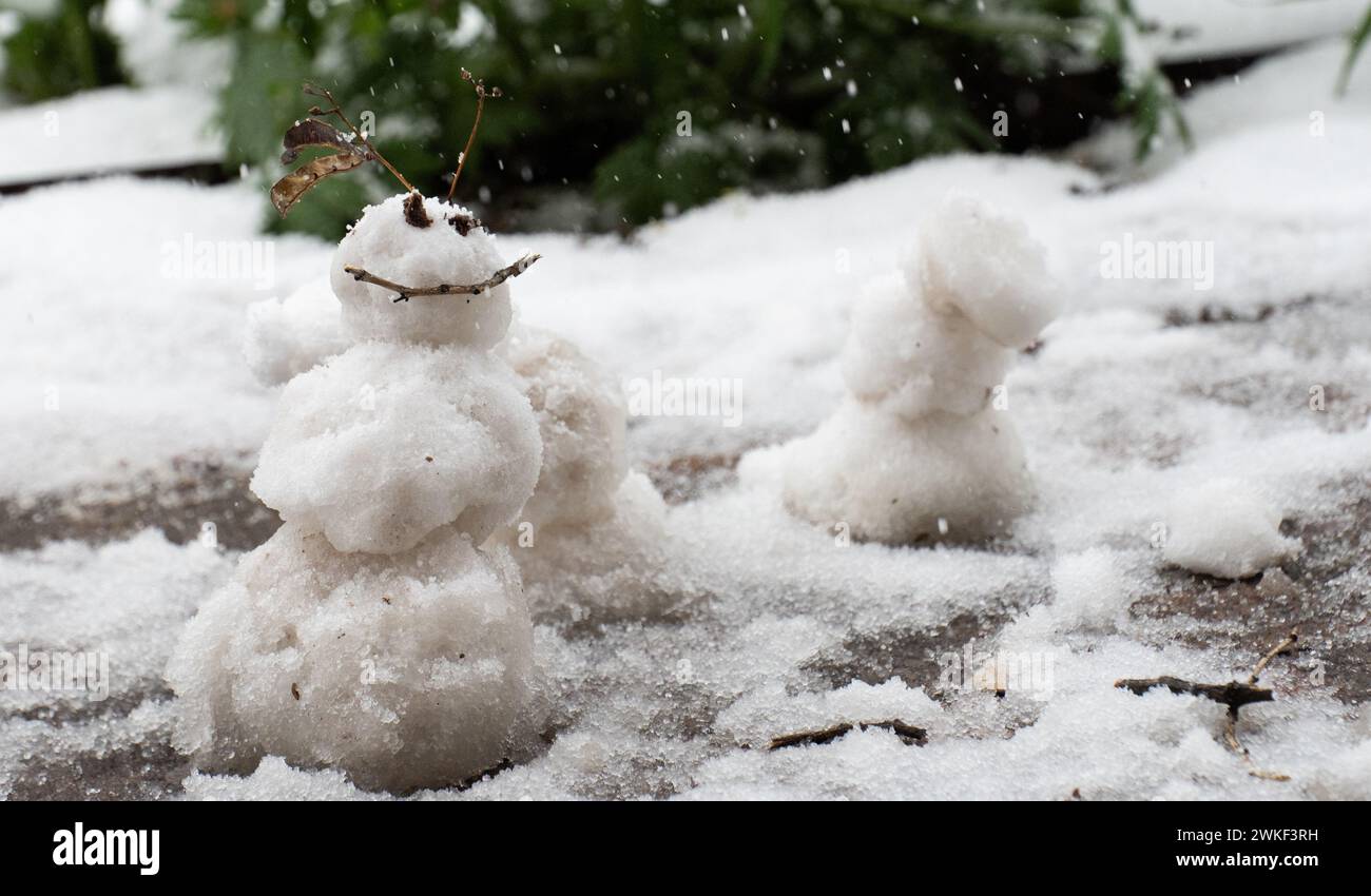 Kleiner winziger weißer Schneemann zwei Augen und Gesicht glückliches Lächeln Glück Winterschnee Lächeln von Stock Augen von kleinen Kieselsteinen Miniatur Schneemann aus Frühlingsschnee Stockfoto