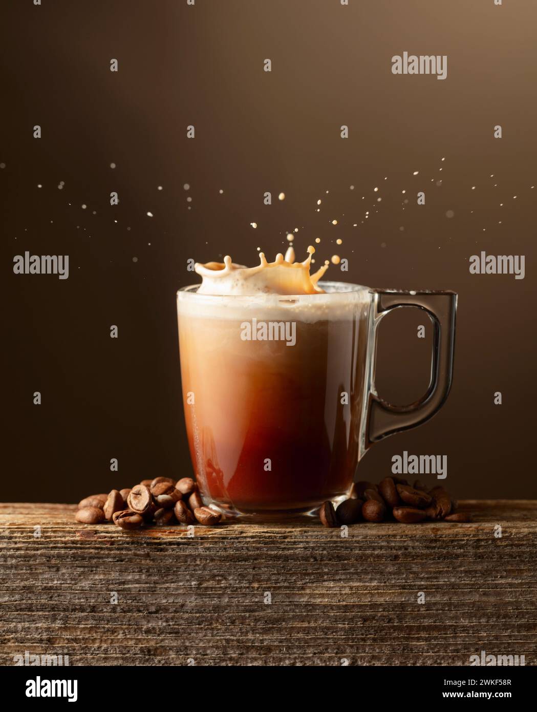 Kaffee- und Schokoladengetränk mit Creme auf braunem Hintergrund. Glas Tasse Kaffeegetränk mit Spritzern. Stockfoto