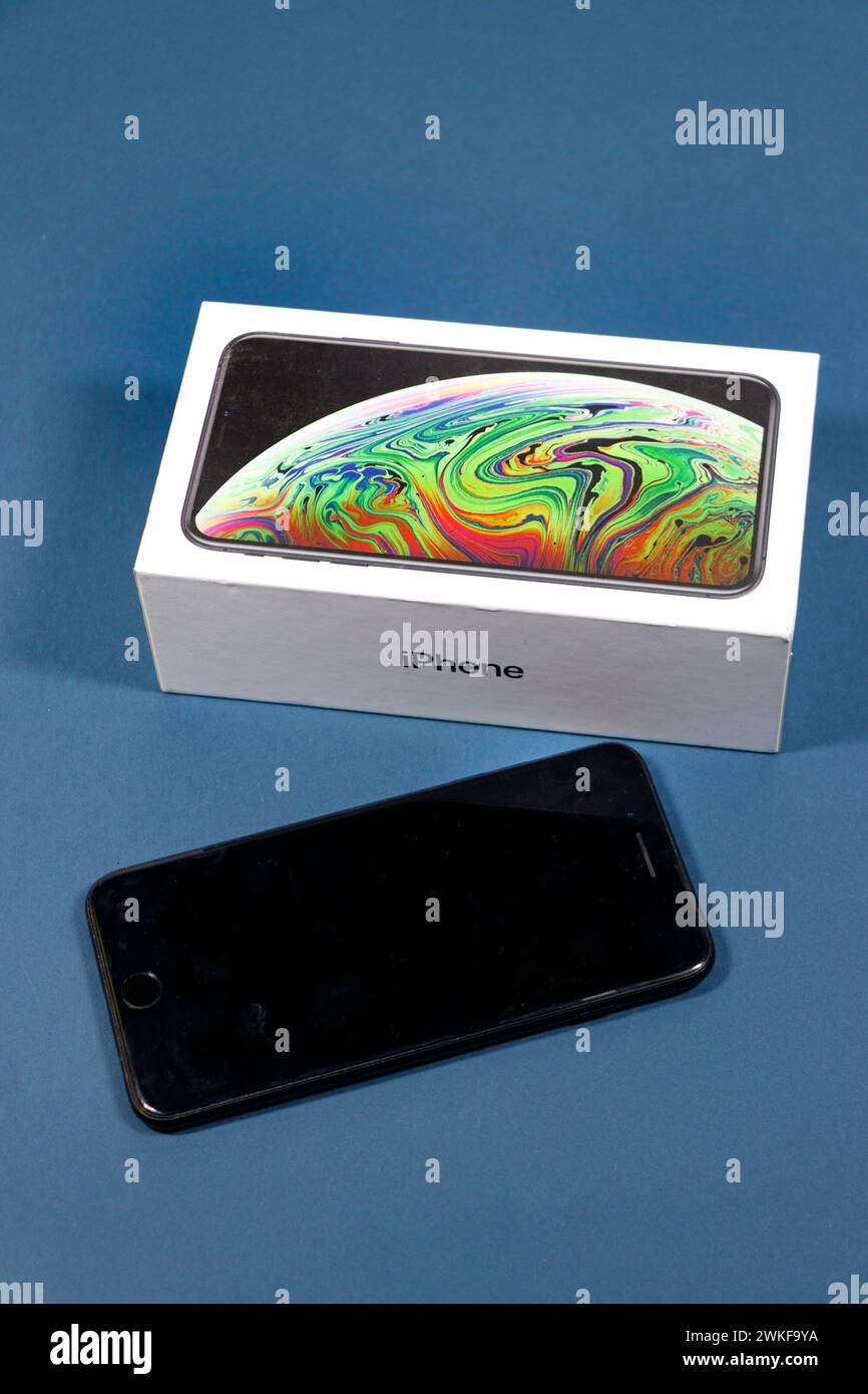 Apple iphone und seine Verpackungsbox auf blauem Studiohintergrund Stockfoto