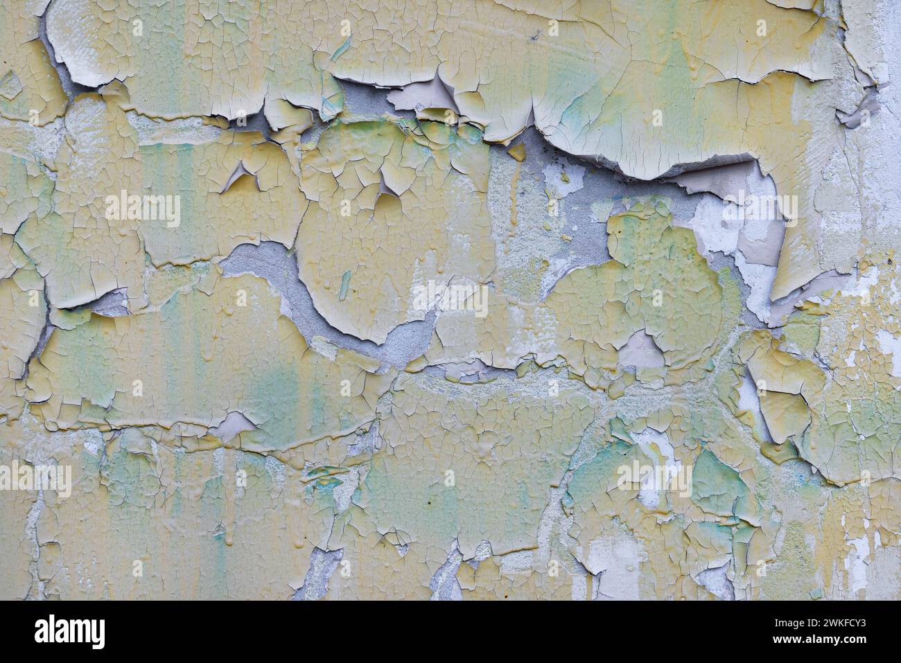 Große Stücke verblasster gelber Farbe fallen von der alten Betonoberfläche. Die Auswirkungen von Verlassenheit und Zerstörung. Stockfoto