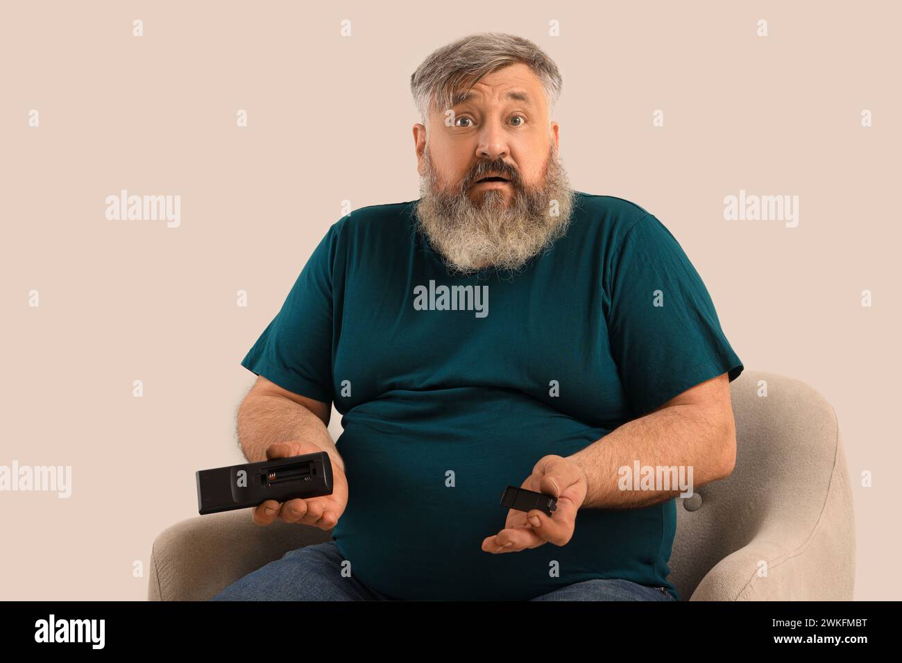 Schockierter reifer Mann mit Fernbedienung ohne Batterien auf hellem Hintergrund Stockfoto