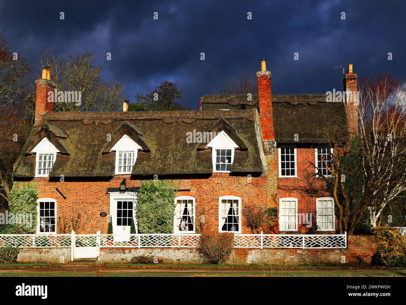 Unter einem stürmischen Himmel entlang des Flusses, der in Wainfleece All Saints in Lincolnshire fließt, steht dieses schöne reetgedeckte Häuschen. Stockfoto