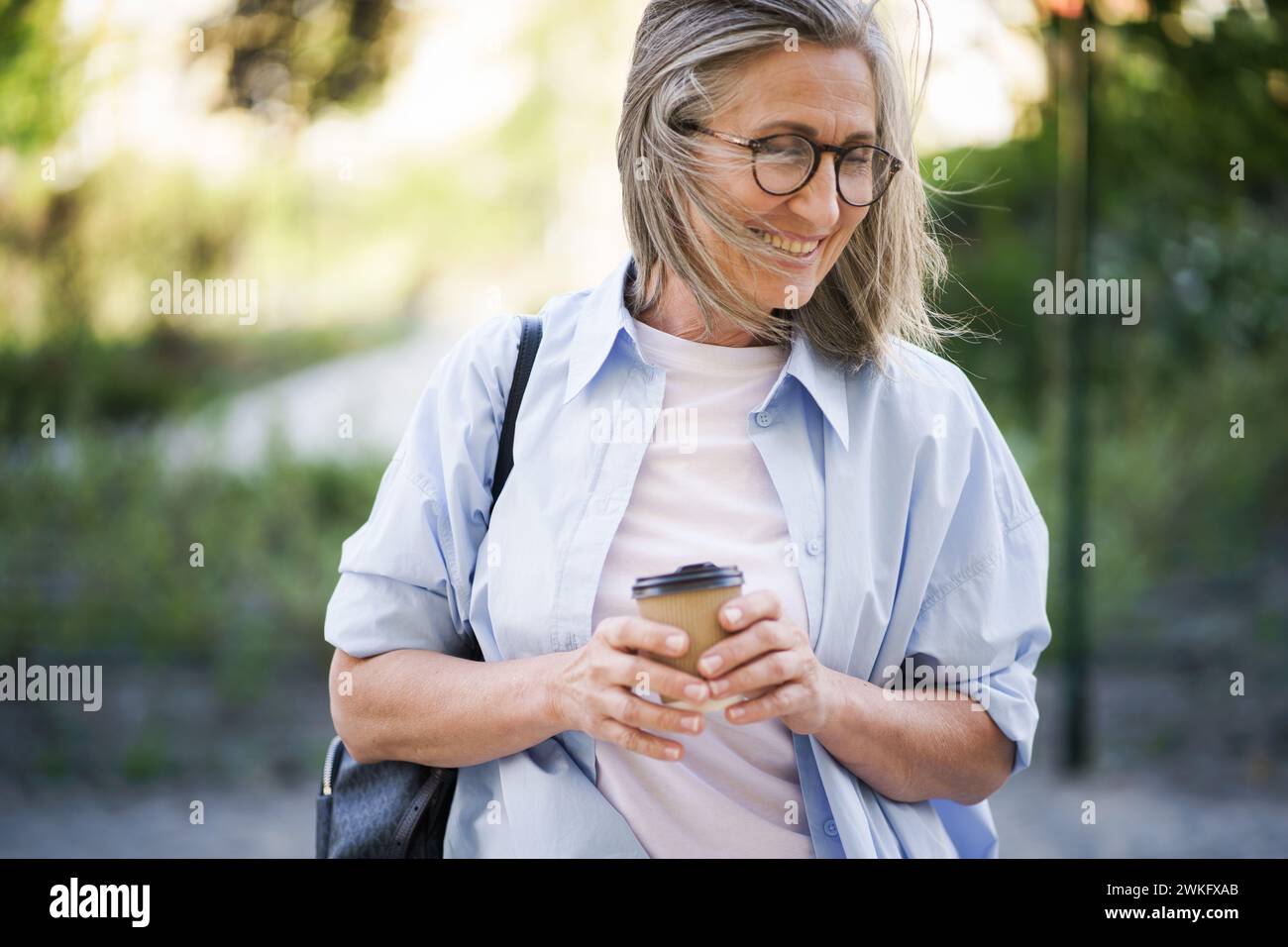 Eine Frau, die eine Brille trägt, konzentriert sich auf ihre Tasse Kaffee, absorbiert in das, was sie trinkt. Stockfoto