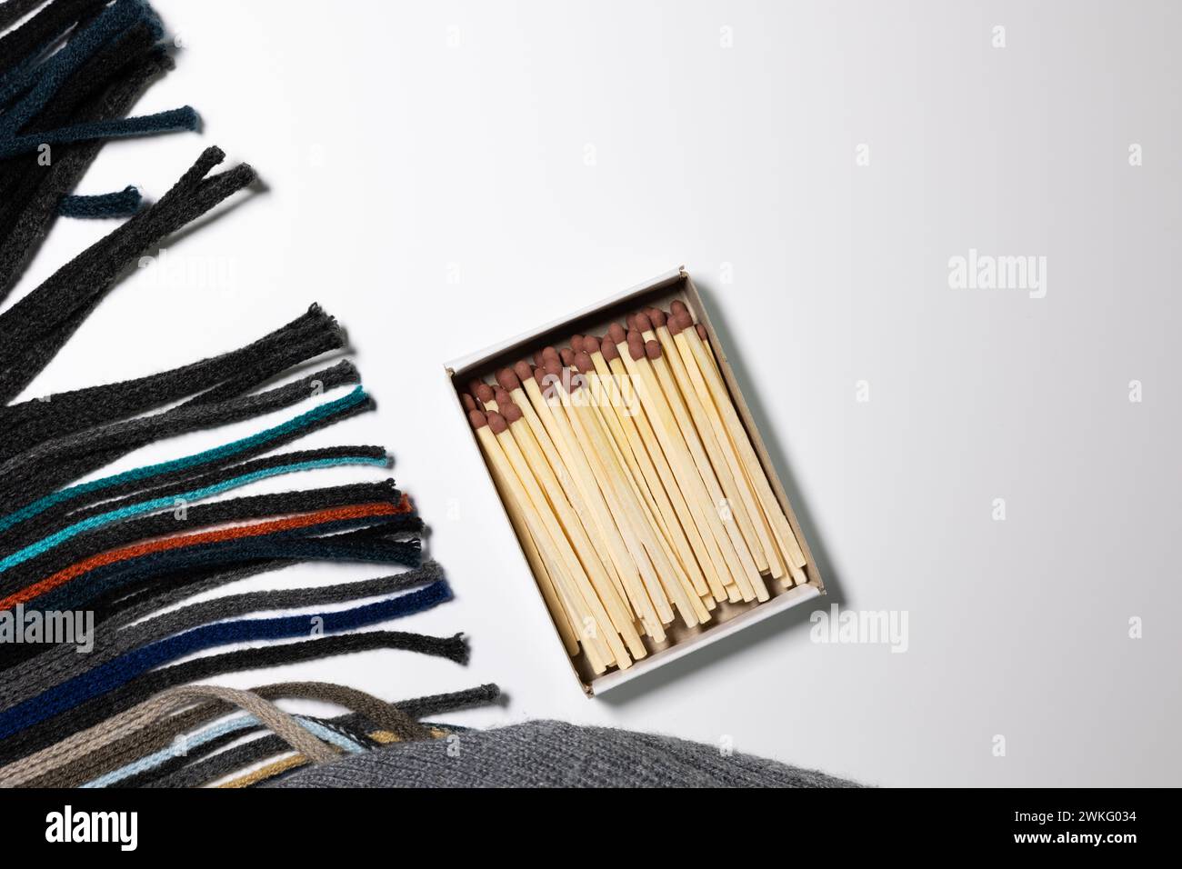 Allgemeiner flacher Lay mit Streichhölzern in einer Box, Schal und Mütze gestricktem Stoff auf weißem Hintergrund. Winterkonzept Stockfoto
