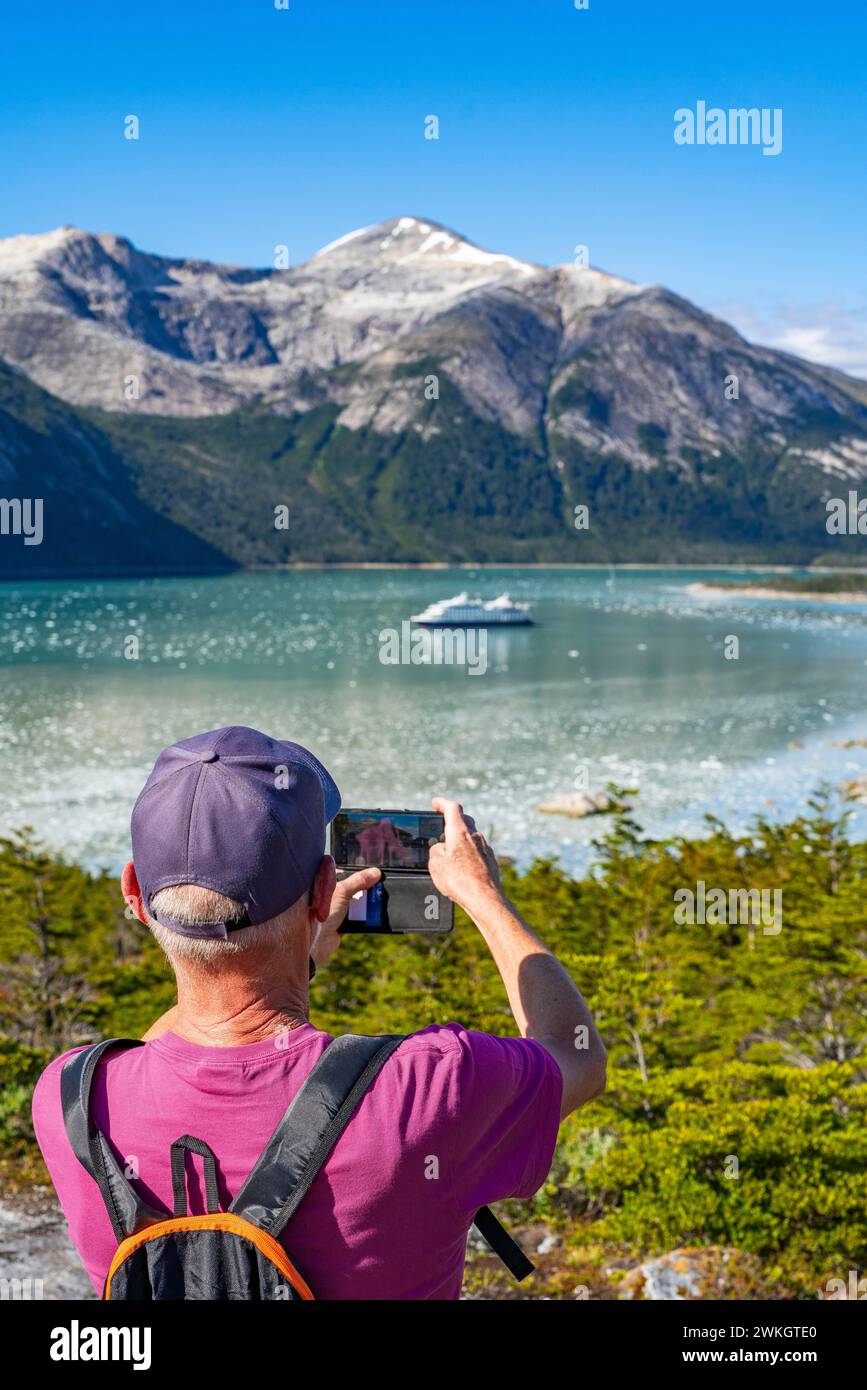 Mann fotografiert das Kreuzfahrtschiff Stella Australis in der Bucht von Pia vor dem Pia-Gletscher, Alberto de Agostini-Nationalpark, Avenue der Gletscher Stockfoto