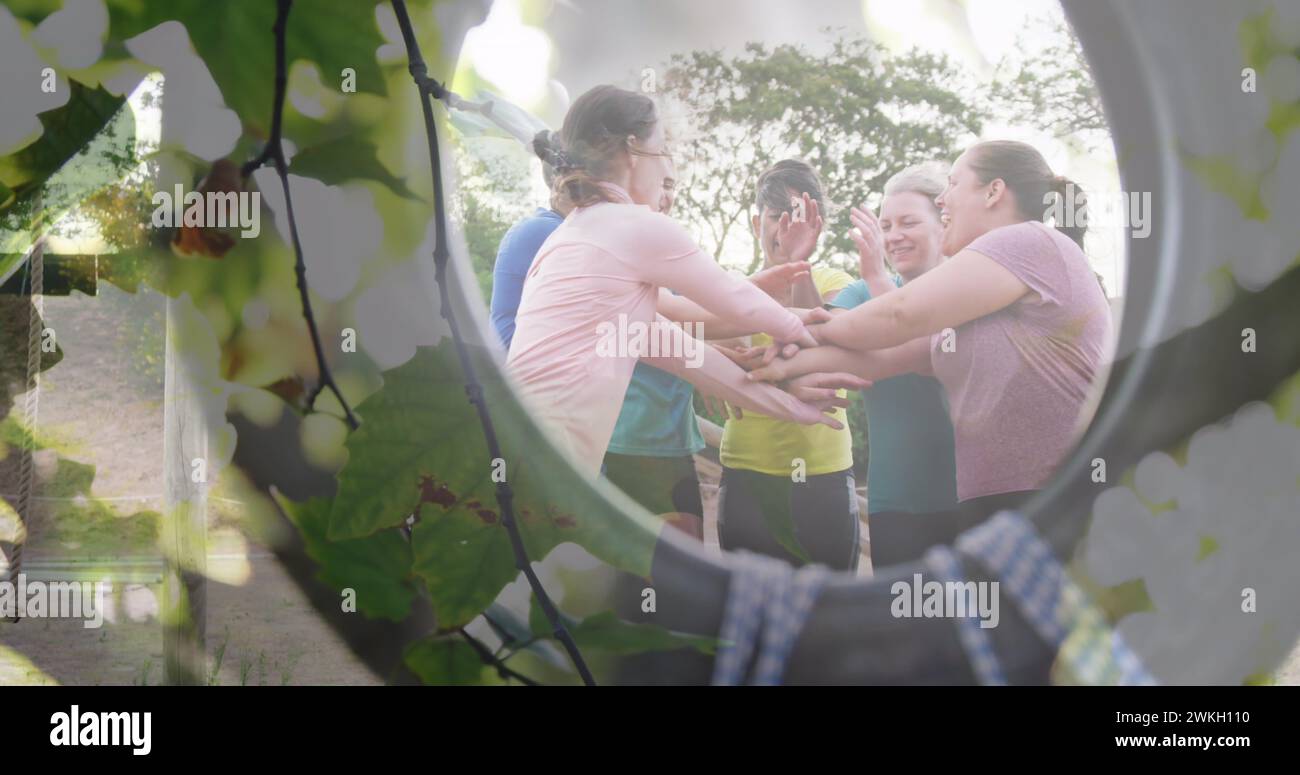 Bild von Blättern über glücklichen Sportfrauen, die sich zusammenschließen Stockfoto