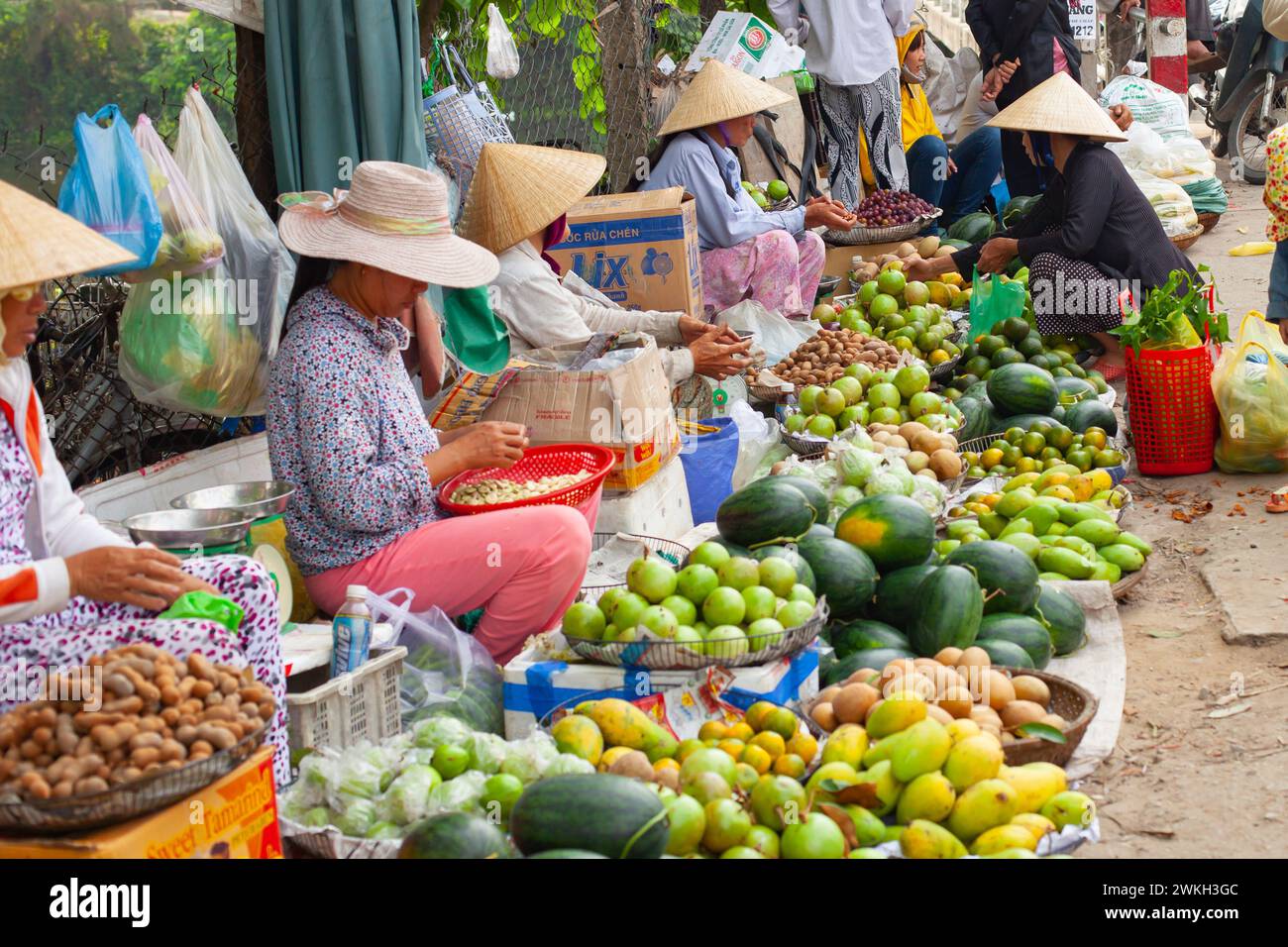 Hue City, Vietnam 21. März 2015: Frauen mit traditionellen Hüten verkaufen auf einem belebten traditionellen Straßenmarkt farbenfrohe Früchte Stockfoto
