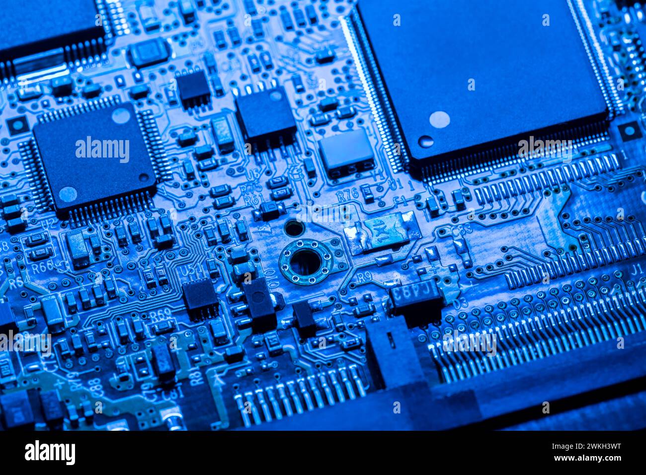 Computerplatine mit Chips und verschiedenen elektronischen Bauteilen. Blau gefärbt. Nahansicht. Stockfoto