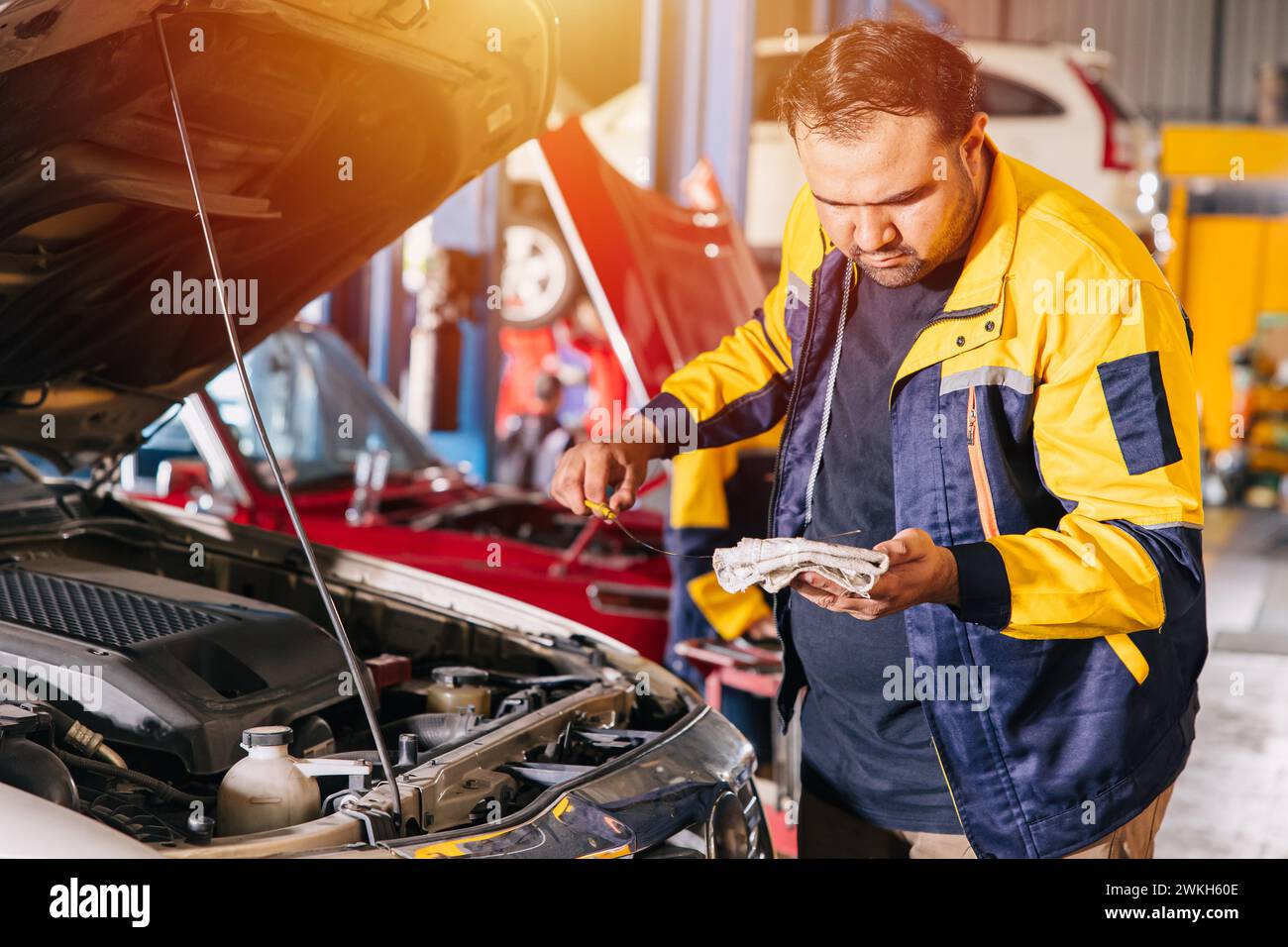 Mann, der den Motorölstand in der Werkstatt überprüft. Mechaniker arbeiten in der Werkstatt an einem Servicewagen Stockfoto