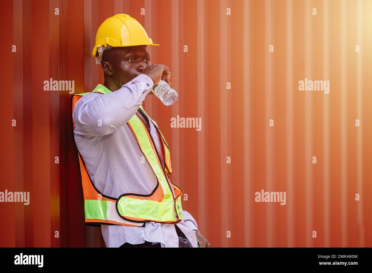 Afrikanische schwarze Arbeiter-Männerbremse Entspannen Sie Trinkwasser, um sich von harter Arbeit in der heißen Sommersaison zu erfrischen Stockfoto