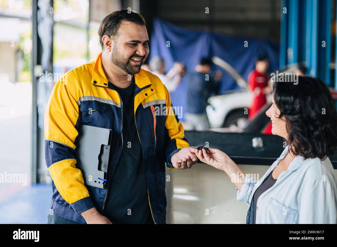Kundenfrauen freuen sich, den Autoschlüssel an Mechaniker zu geben, um das Problem zu beheben, Auto Center Werkstatt Center Stockfoto
