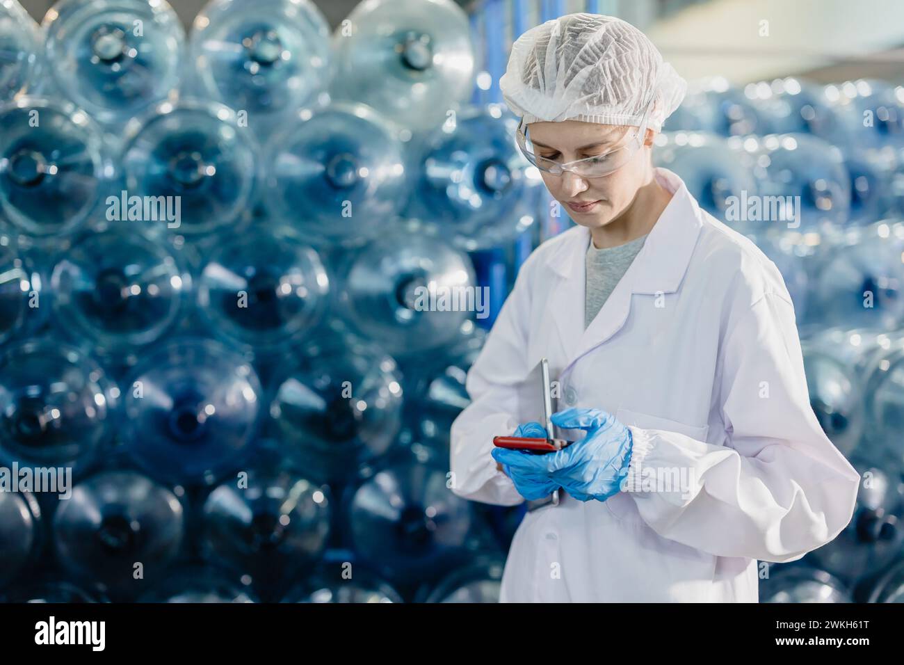 Leitende Arbeitnehmerinnen arbeiten in Trinkwasserfabrik Zählen Wasserflaschen-Gallonen-Vorrat an hygienisch einheitlichen Arbeitsplätzen Stockfoto