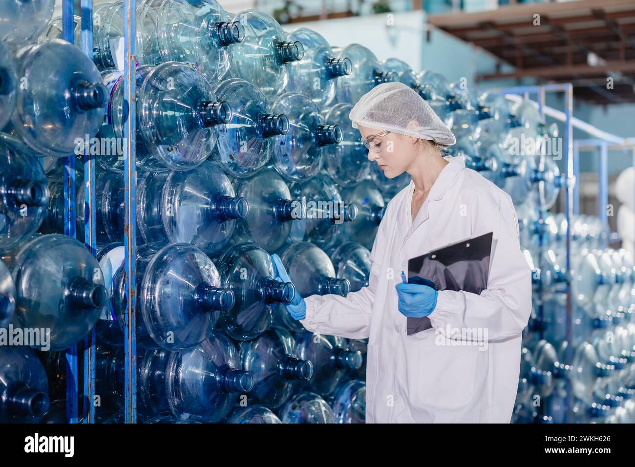 Arbeitnehmerinnen, die in der Trinkwasserfabrik arbeiten, prüfen Zählen der Flasche Gallonen Lagerkontrolle Zählen mit Hygieneuniform. Stockfoto