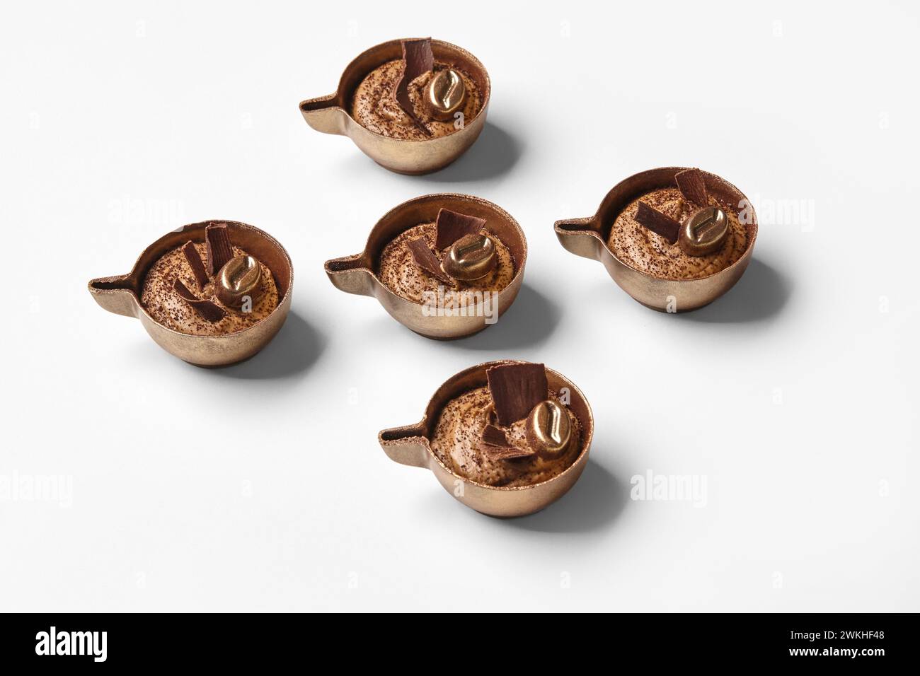 Handgemachte Schokoladenbonbons mit reichhaltiger Kaffeesahne, künstlerisch gestaltet, um wie kleine Kaffeetassen vor weißem Hintergrund aussehen zu lassen Stockfoto