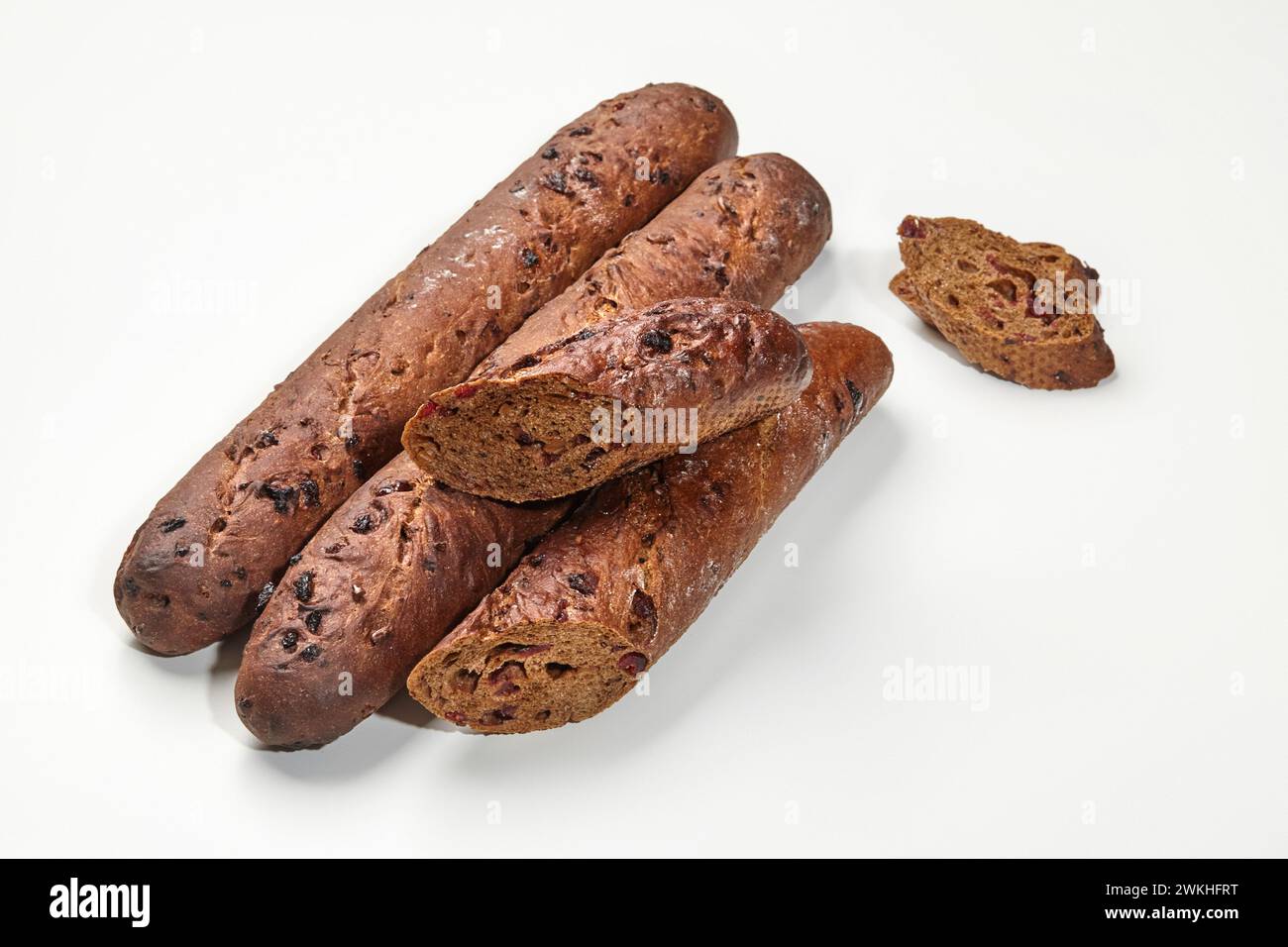 Dunkle Roggen-Baguette-Brote mit säuerlichen Preiselbeeren, in detaillierter Nahaufnahme auf weißem Hintergrund. Konzept für handwerkliche Backwaren Stockfoto
