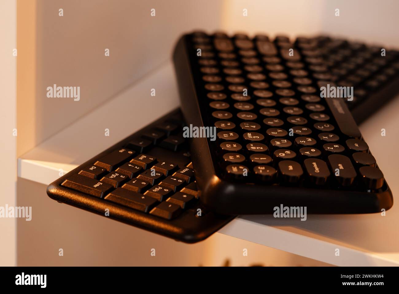 Zwei schwarze drahtlose Tastaturen auf einem Regal Stockfoto