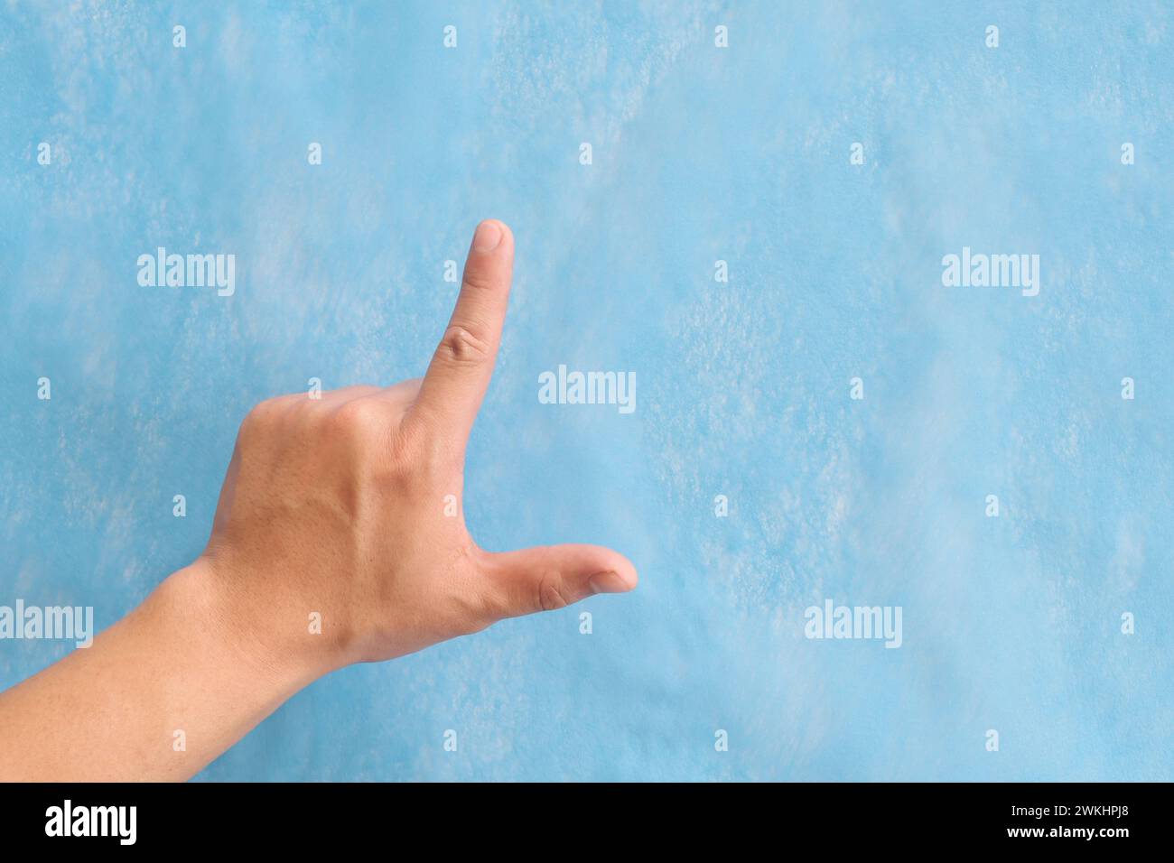 Junge männliche asiatische Hand, die Loser-Zeichen oder Buchstaben L isoliert auf blauem Hintergrund macht. Stockfoto