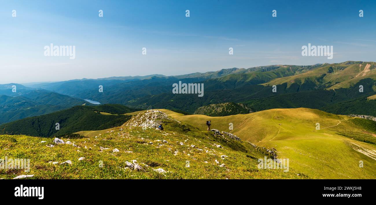 Fantastische Aussicht während der Wanderung in den Valcan Bergen in Rumänien mit dem Iovanuli See ILacul und vielen Hügeln während des wunderschönen Sommernachmittags Stockfoto