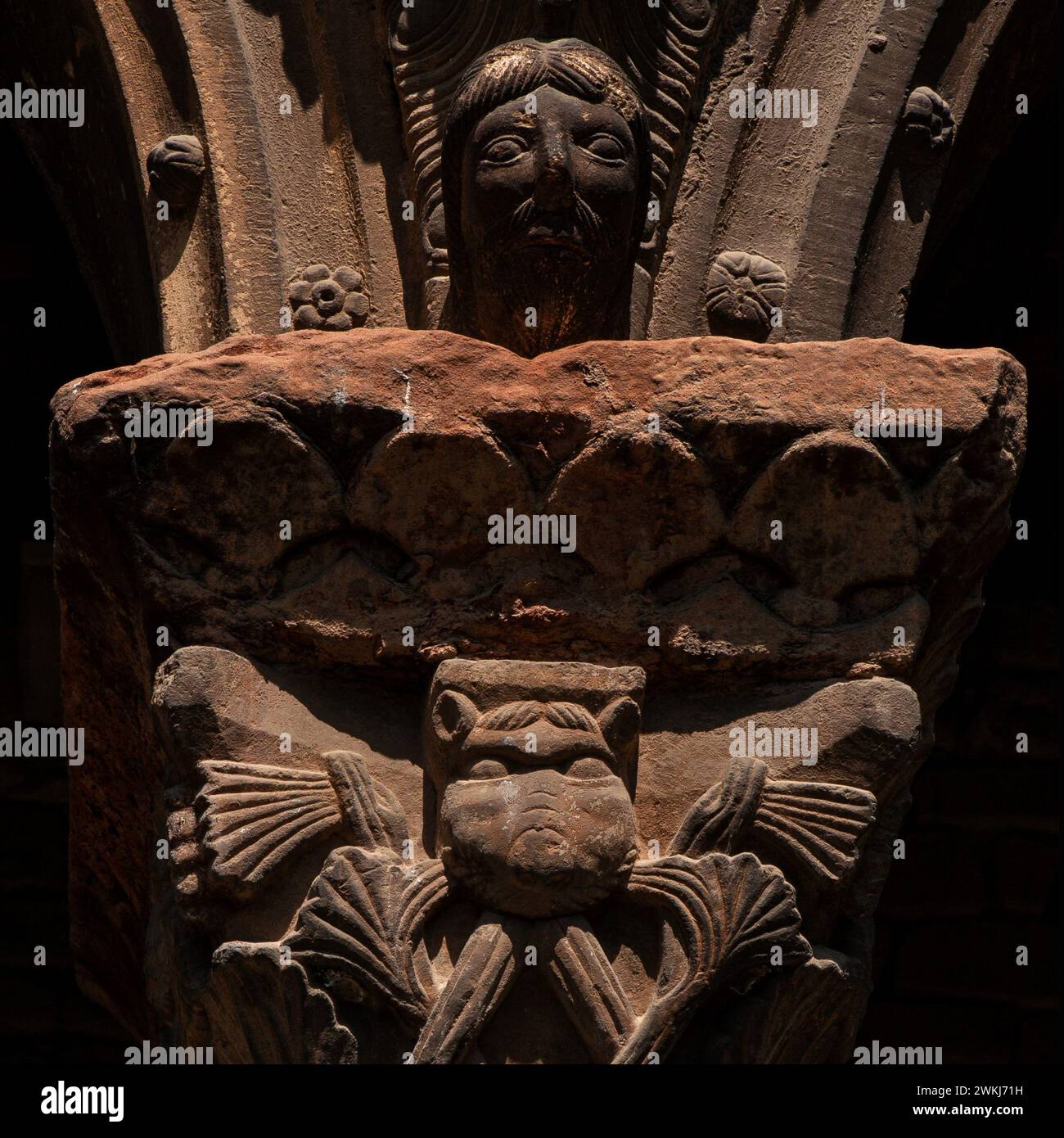 Ein menschliches Gesicht und eine fantastische Kreatur. Lombardische romanische Steinhauptstadt auf der unteren Ebene des Klosters Santa Maria de Ripoll in der Provinz Girona, Katalonien, Spanien. Stockfoto