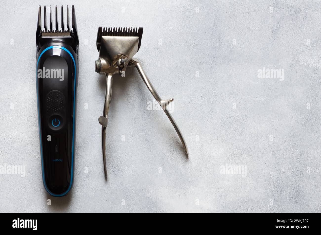Alte und neue Haarschneider- und Rasierutensilien auf weißem rustikalem Hintergrund, Friseurzubehör Stockfoto
