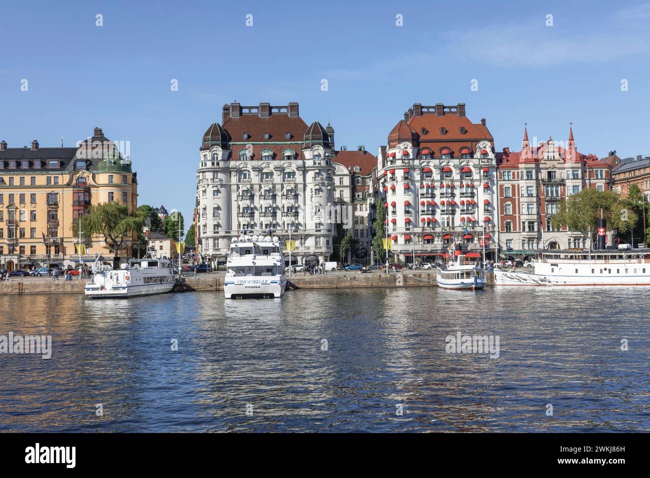 Historische Gebäude am Strandvagen 7 sind das Hotel Esplanade (l) und das Hotel Diplomat (r) hinter Booten und Fähren in Nybroviken, Ostermalm, Stockholm Stockfoto