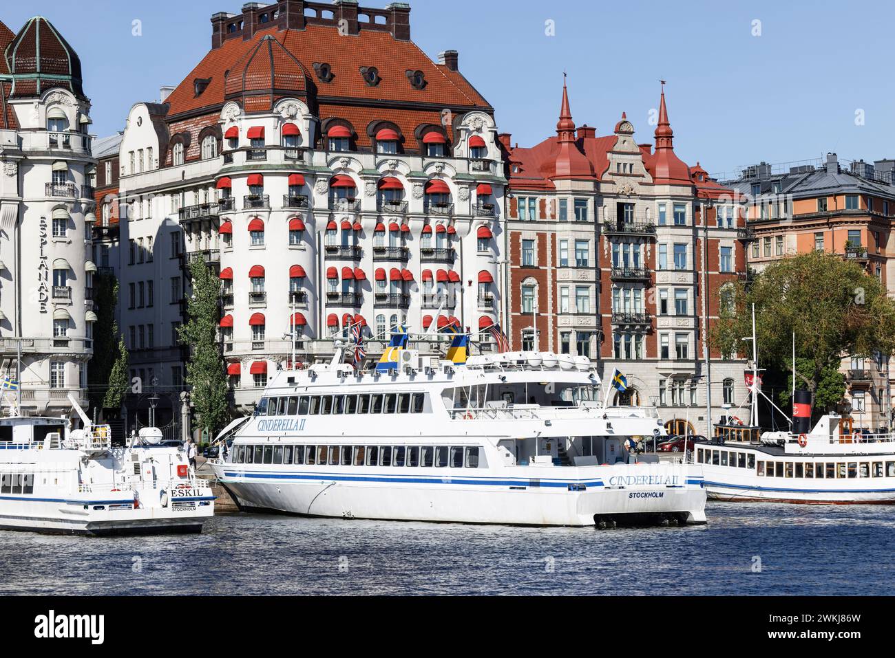 Historische Gebäude im Jugendstilhotel Strandvagen 7 Diplomat (rotes Baldachin) hinter Booten und Fähren in Nybroviken, Ostermalm, Stockholm Stockfoto