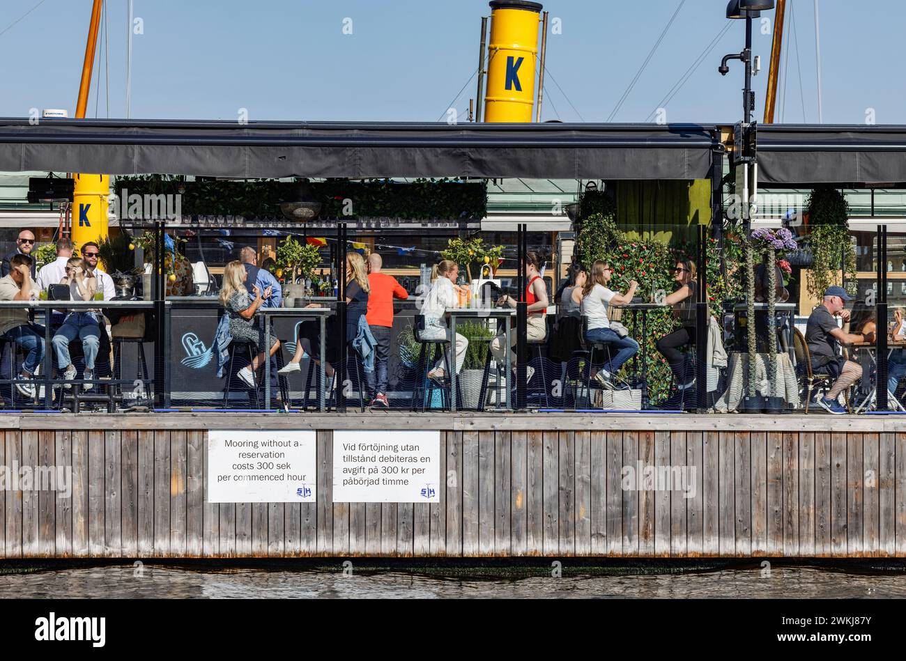 Menschen in Bars und Cafés am Wasser an der historischen Strandvagen Promenade am Ladugårdslandsviken See, Ostermalm, Stockholm Stockfoto