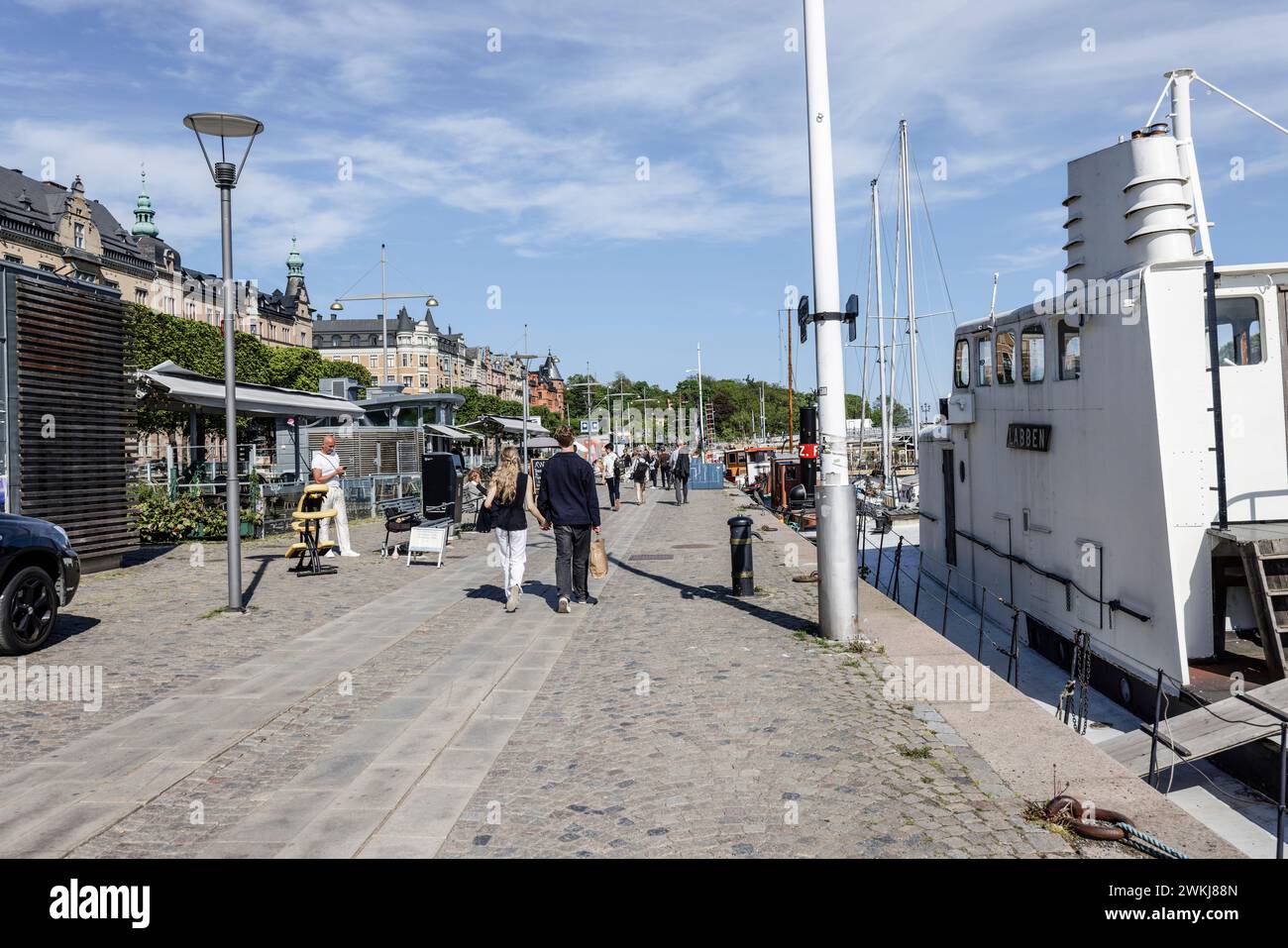 Auf der historischen Strandvagen-Uferpromenade spazieren die Menschen an Cafés, Bars und Booten im Ladugårdslandsviken-See, Ostermalm, Stockholm Stockfoto