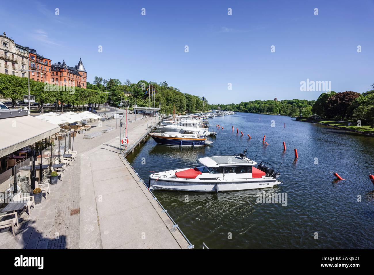 Boote, die an der Strandvägen-Kai-Promenade auf dem historischen, baumbestandenen Boulevard vor Anker liegen, an Gebäuden in Bajonetten-Gegend in Ostermalm, Stockholm. Stockfoto