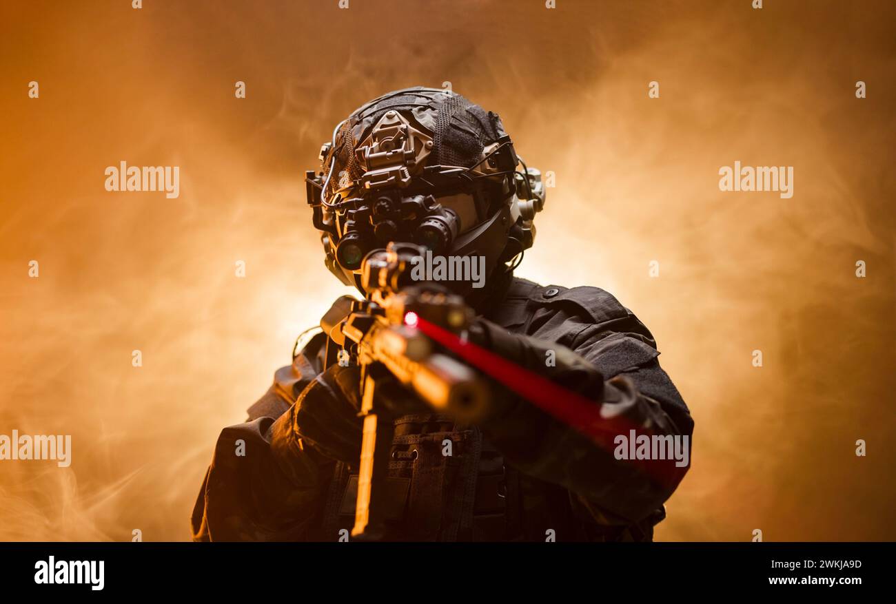 Ein fokussierter Mann, der eine Waffe in der Hand hält. Soldat in voller professioneller Armee-Ausrüstung vor Nebelhintergrund mit blinkender Hintergrundbeleuchtung. Stockfoto