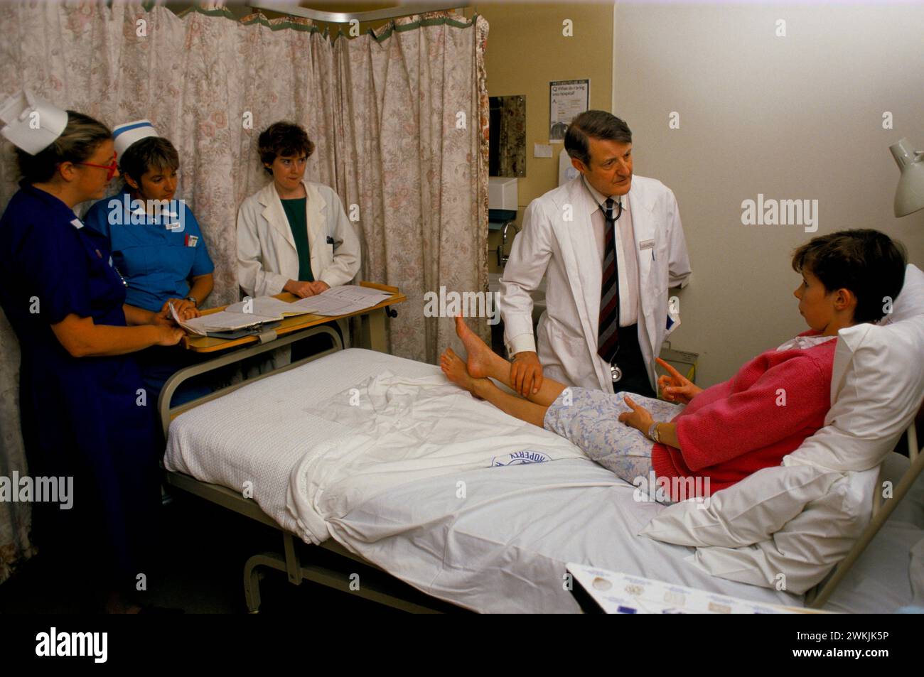 Bath, Somerset, England 1988. Der Berater Herr Bamford, Dr. Maura Stafford und die Krankenschwester und die Matronin sprechen mit einem Patienten während einer Ward Round. Royal United Hospital Bath. HOMER SYKES AUS DEN 1980ER JAHREN Stockfoto