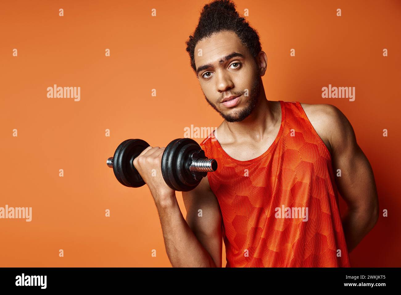 Attraktiver sportlicher afroamerikaner im Uniformtraining mit Kurzhantel und Blick in die Kamera Stockfoto