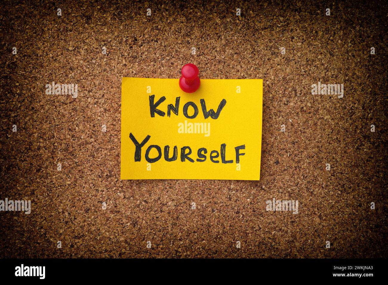 Eine gelbe Papiernote mit dem Satz "Know Yourself" drauf, die an ein Korkbrett geheftet ist. Nahaufnahme. Stockfoto